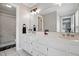 A bright bathroom has a double sink vanity, large mirror, and tiled shower with a marble pattern at 4600 Smithfield Rd, Wendell, NC 27591