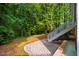 Landscaped backyard with a stone patio, lush greenery, and wooded views at 507 Vatersay Dr, Apex, NC 27502