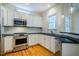Updated kitchen featuring white cabinets, stainless steel appliances, and hardwood floors at 507 Vatersay Dr, Apex, NC 27502