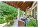 Outdoor back porch featuring wood flooring, ceiling fans, comfortable seating, and lush landscaping at 671 Bear Tree Crk, Chapel Hill, NC 27517