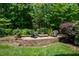 Relaxing backyard patio featuring a fire pit area with outdoor seating surrounded by mature trees at 671 Bear Tree Crk, Chapel Hill, NC 27517