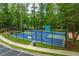 Outdoor basketball court with blue and green surfaces, black fencing, and maintained landscaping at 671 Bear Tree Crk, Chapel Hill, NC 27517