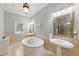 Spacious bathroom with marble tile, separate sinks, large soaking tub, and elegant lighting fixtures at 671 Bear Tree Crk, Chapel Hill, NC 27517