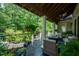 Large covered porch with plush seating, outdoor fireplace, and lots of potted flowers and plants at 671 Bear Tree Crk, Chapel Hill, NC 27517