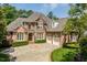 Traditional brick home featuring manicured landscaping, circular driveway, and attached two car garage at 671 Bear Tree Crk, Chapel Hill, NC 27517