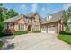 Stately brick home with manicured landscaping, arched windows, and a circular driveway at 671 Bear Tree Crk, Chapel Hill, NC 27517