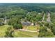 Aerial view of a golf course with well-manicured greens, mature trees, and the clubhouse with outdoor seating at 671 Bear Tree Crk, Chapel Hill, NC 27517