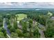 Aerial view of a golf course featuring a clubhouse, lake view, and well-manicured greens at 671 Bear Tree Crk, Chapel Hill, NC 27517