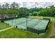 View of outdoor tennis courts with green surfaces, black fencing, and manicured lawn at 671 Bear Tree Crk, Chapel Hill, NC 27517