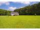 Spacious backyard with a large, green lawn and a view of the surrounding trees at 6916 Morrow Mill Road, Chapel Hill, NC 27516