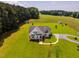 Exterior elevation of a charming, light-gray home featuring well-manicured lawn and gravel driveway on expansive acreage at 6916 Morrow Mill Road, Chapel Hill, NC 27516