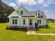 Charming front exterior of a light-gray home featuring a well-manicured lawn, blue front door and stone walkway at 6916 Morrow Mill Road, Chapel Hill, NC 27516