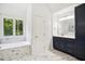 Well-lit bathroom with a soaking tub, navy vanity and marble style floors at 7309 New Forest Ln, Wake Forest, NC 27587