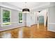 Bright dining room with hardwood floors, two large windows, modern light fixture, and access to foyer at 7309 New Forest Ln, Wake Forest, NC 27587