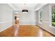 Bright dining room with hardwood floors, large window, modern light fixture, and access to kitchen at 7309 New Forest Ln, Wake Forest, NC 27587