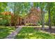 Two story brick home with black front door surrounded by mature trees and a green lawn at 7309 New Forest Ln, Wake Forest, NC 27587