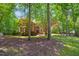 Two story brick home surrounded by mature trees and a green lawn on a sunny day at 7309 New Forest Ln, Wake Forest, NC 27587