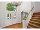Bright foyer with chandelier, wooden floors, staircase, and double doors with transom window at 7309 New Forest Ln, Wake Forest, NC 27587