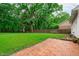 Large backyard with a brick patio and mature trees at 8505 Stonegate Dr, Raleigh, NC 27615