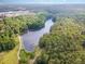 An aerial view captures a serene lake surrounded by lush forest, walking paths, and a dock at 8816 Valley Springs Pl, Raleigh, NC 27615