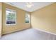Bedroom with neutral carpet, paint, and trim, and two windows providing natural light at 921 Shefford Town Dr, Rolesville, NC 27571
