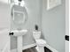 Powder room featuring pedestal sink, round mirror, and a modern toilet at 97 Arapahoe Dr, Kenly, NC 27542
