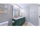 Chic bathroom with dual sinks, a green vanity, wallpaper accent wall, and modern fixtures at 973 Rebecca Ln, Siler City, NC 27344