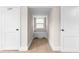 Hallway with storage bench and window nestled between bedroom closets, carpeted flooring, and neutral color palette at 1001 N Orange Ave, Dunn, NC 28334