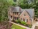Aerial view of a two-story brick home surrounded by lush landscaping and mature trees at 1004 Staffield Lane Ln, Chapel Hill, NC 27516