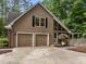 Two-car garage with brown siding adjacent to a brick home in a wooded setting at 1004 Staffield Lane Ln, Chapel Hill, NC 27516