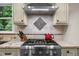 Close-up of a kitchen range and hood with granite countertops and stone backsplash at 1004 Staffield Lane Ln, Chapel Hill, NC 27516