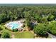 Aerial view of community pool, clubhouse, tennis courts, parking, and manicured lawns surrounded by trees at 105 Spring Bud Dr, Cary, NC 27513