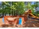 Community play area with a wooden sandbox and a playground visible in the background, surrounded by tall trees at 105 Spring Bud Dr, Cary, NC 27513