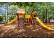 Community playground featuring slides, climbing wall, and swing set, surrounded by mature trees and a wood chip ground covering at 105 Spring Bud Dr, Cary, NC 27513