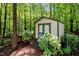 Outdoor storage shed with double doors nestled among lush greenery and mature trees in a wooded backyard at 105 Spring Bud Dr, Cary, NC 27513