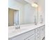 Bright bathroom featuring double sinks, white cabinets, and a large mirror at 112 Filigree Way, Durham, NC 27713