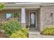 A welcoming front entrance features a glass paneled door, brick facade, with meticulously trimmed landscaping at 112 Filigree Way, Durham, NC 27713
