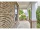 Side view of the covered front porch with brick columns and manicured shrubs at 112 Filigree Way, Durham, NC 27713