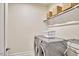 Well-lit laundry room with modern washer and dryer set and overhead shelving at 112 Filigree Way, Durham, NC 27713