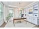 Well-lit home office featuring custom built-ins, hardwood floors, and a classic chandelier at 112 Filigree Way, Durham, NC 27713