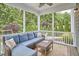 Relaxing screened porch with a comfortable sectional sofa, coffee table, and wooded views at 112 Filigree Way, Durham, NC 27713