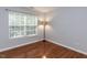 Bedroom showcasing hardwood floors, a large window, and a modern standing lamp at 122 Button Rd, Morrisville, NC 27560
