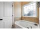 Bathroom with a large soaking tub under an arched window, with a white door to the left at 13 Nettletree Creek Ct, Youngsville, NC 27596