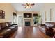 Inviting living room featuring hardwood floors, stone fireplace, leather sofas, ceiling fan, and ample natural light at 13 Nettletree Creek Ct, Youngsville, NC 27596