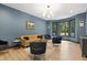 Elegant living room with blue walls, a mustard-colored couch, and large windows with backyard views at 13121 Melvin Arnold Rd, Raleigh, NC 27613