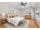Bright bedroom with a large bed, a ceiling fan, and ensuite bathroom that has a framed mirror at 1480 Big Leaf Loop, Apex, NC 27502