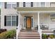 Inviting front porch with wood decking, white railings, and decorative columns leading to the front door at 1480 Big Leaf Loop, Apex, NC 27502