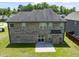 A well-maintained backyard with a brick home, a small concrete patio, and a lush green lawn at 1499 Fireside Ln, Creedmoor, NC 27522