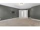 Large bedroom featuring neutral carpet, gray walls, white trim, and two open doors at 1499 Fireside Ln, Creedmoor, NC 27522