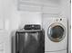 Bright laundry room featuring a black washing machine and a white dryer and shelving at 1499 Fireside Ln, Creedmoor, NC 27522
